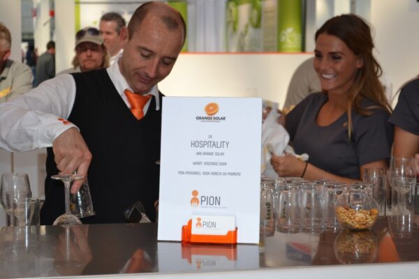 PION horeca promotie uitzendbureau Bergen op Zoom Personeel collega meewerken medewerker op beur met oranje Soler drankje hospitality